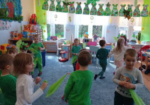 Dzieci tańczą z zielonymi chusteczkami.